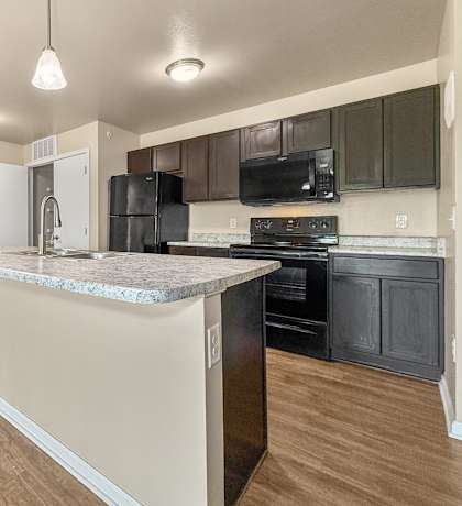 A kitchen with a marble countertop and black appliances.