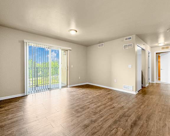 A room with wooden flooring and sliding glass doors.