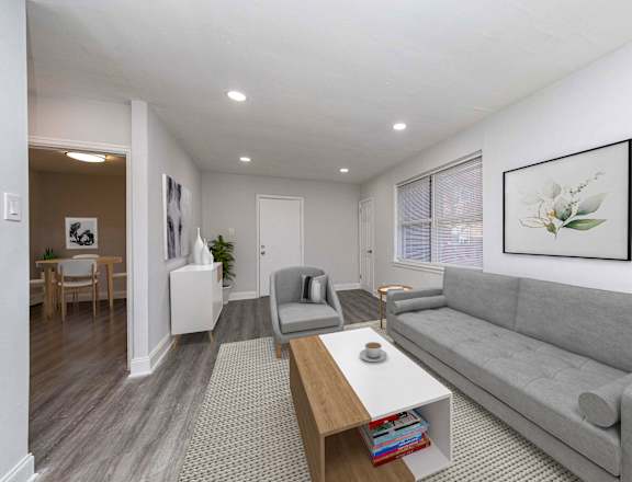 A living room with a grey couch, a coffee table, and a painting on the wall.at Lawndale Apartments, Philadelphia