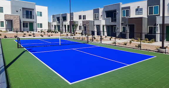 A tennis court in front of a row of houses.