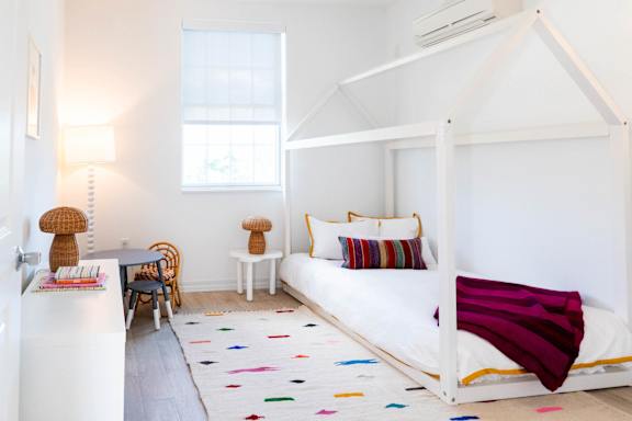 A white bedroom with a white bed and a white chair.