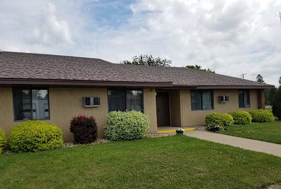 A house with a brown roof and a green lawn in front.