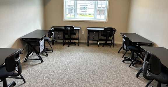 an empty classroom with tables and chairs and a window