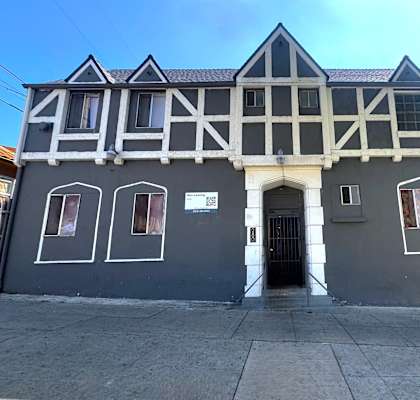 A building with a black and white facade has a black door and windows.