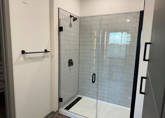 a white tiled shower in a bathroom with a glass door at The Depot, Missouri, 64083