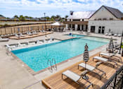 Thumbnail 28 of 32 - A large outdoor swimming pool with sun loungers and a striped umbrella at Alante Homes at Spring Run, Caldwell, 83607