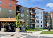 Thumbnail 22 of 27 - Apartment complex with a small tree in front of a building.