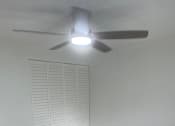 Thumbnail 9 of 28 - A ceiling fan with lights is mounted on a white wall above a white radiator.