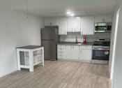 Thumbnail 2 of 28 - A kitchen with a wooden wall and white appliances.