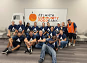 Thumbnail 5 of 5 - A group of people in blue shirts are posing for a photo in front of a sign that says "Atlanta Community Food Bank".