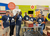 Thumbnail 4 of 5 - A group of people in blue shirts with the logo "AZALEA RESIDENT" are standing in front of a table with boxes on it.