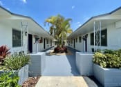 Thumbnail 1 of 5 - a courtyard with white buildings and a palm tree at Lakeside @ Biscayne Gardens,North Miami, FL,33181