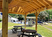 Thumbnail 9 of 17 - A wooden pavilion with picnic tables underneath