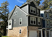 Thumbnail 1 of 18 - A multi-story building with a grey roof and white trim.