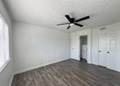Thumbnail 5 of 15 - A room with a ceiling fan and wooden flooring.