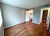 Thumbnail 16 of 28 - A room with wooden flooring and a white door.