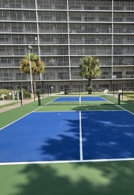 a tennis court with an apartment building in the background