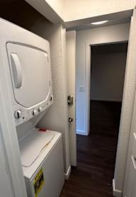 A white washing machine is in a small room with a door on the right.