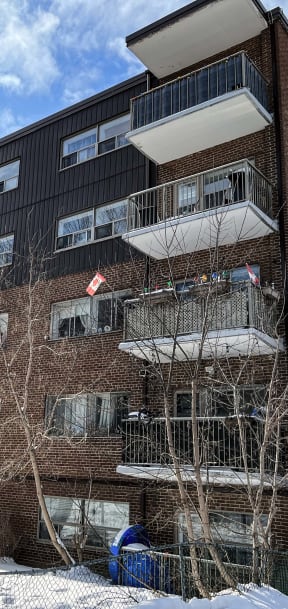 a brick apartment building with balconies and trees in front of it