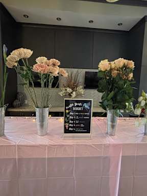 A table with a sign and vases with flowers on it.