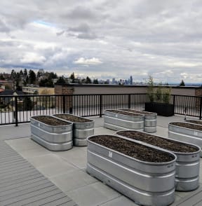 a group of stainless steel planters on a roof with a city in the background