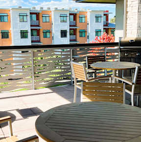 A patio with a table and chairs and a grill.