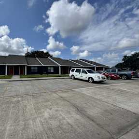 A white car is parked in a parking lot in front of a building.
