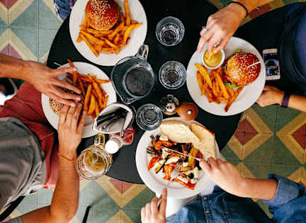 A top view of a group of people sharing a meal with burgers and fries.