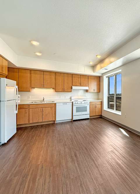 A kitchen with wooden floors and white appliances.