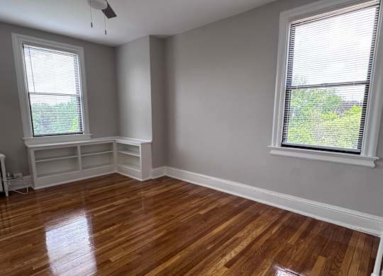 A room with a ceiling fan and wooden floors.