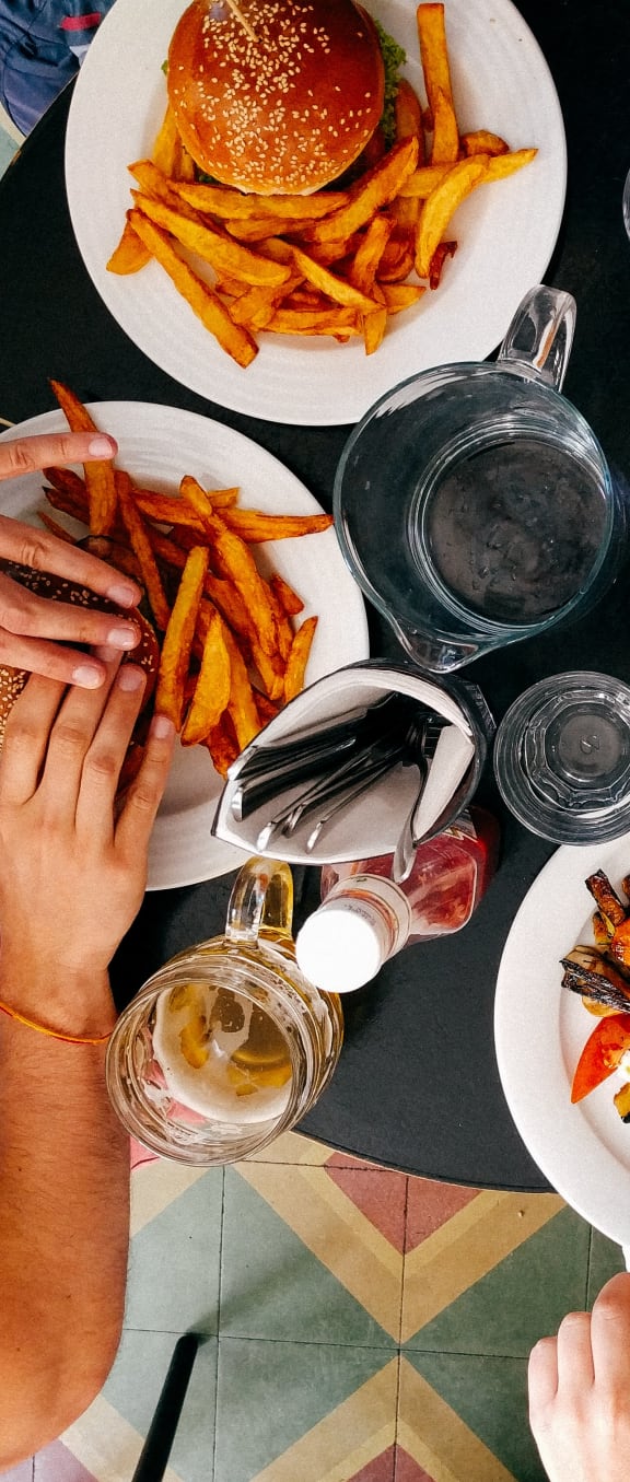 people sitting around a table eating food with burgers and fries