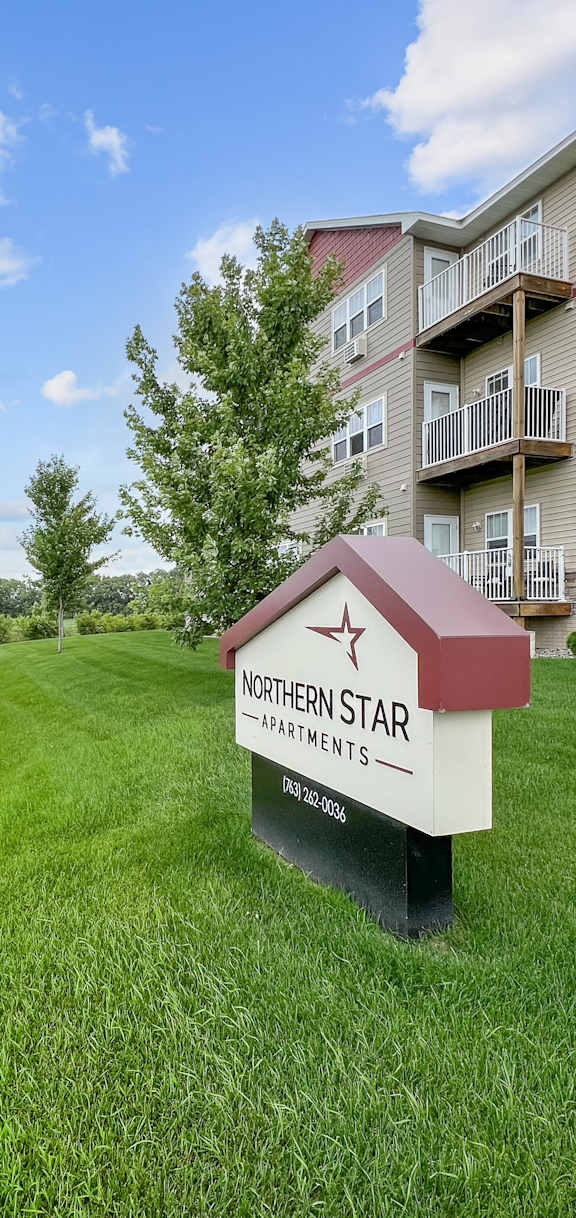 an apartment building with a sign in the grass