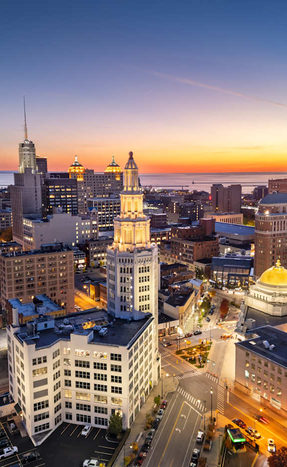 A cityscape at dusk with buildings illuminated and a golden dome structure.