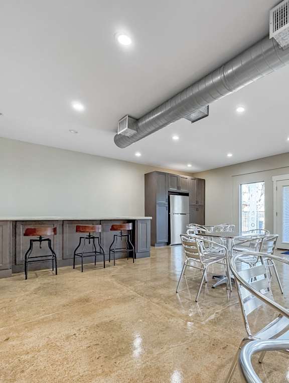 A spacious dining area with a bar and chairs.