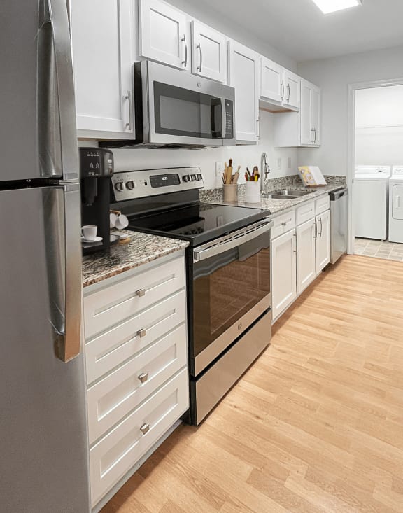 spacious kitchen with stainless steel appliances and white cabinets in an apartment