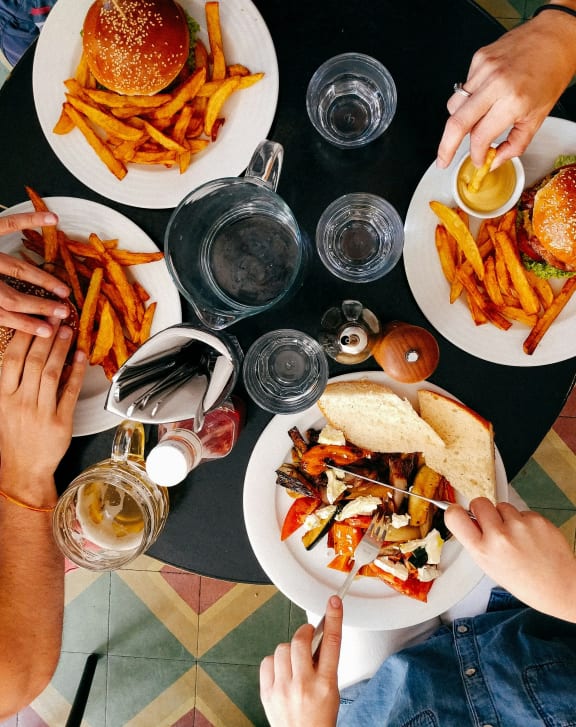 people sitting around a table eating food with burgers and fries