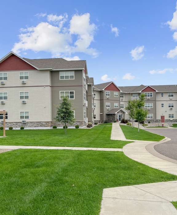 A large apartment complex with a grassy courtyard and a walking path.
