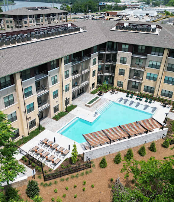 An aerial view of apartment buildings with a pool in the foreground.