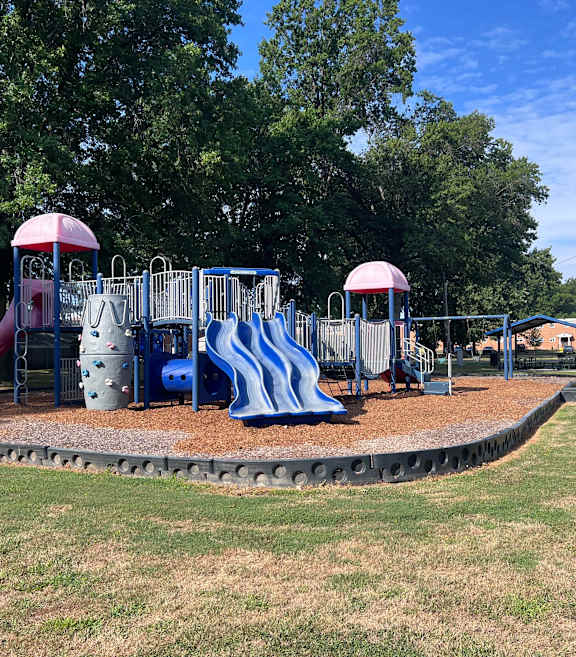 A playground with a blue slide and a red slide at Emerald Village Apartments, Willoughby, OH, Ohio