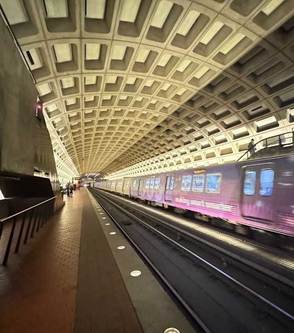 A train is passing through a subway station with a long platform.