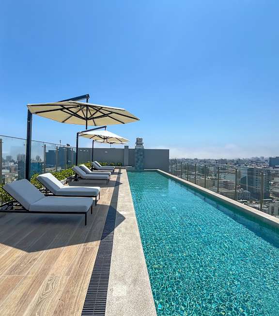 A pool with a wooden deck and sun loungers.