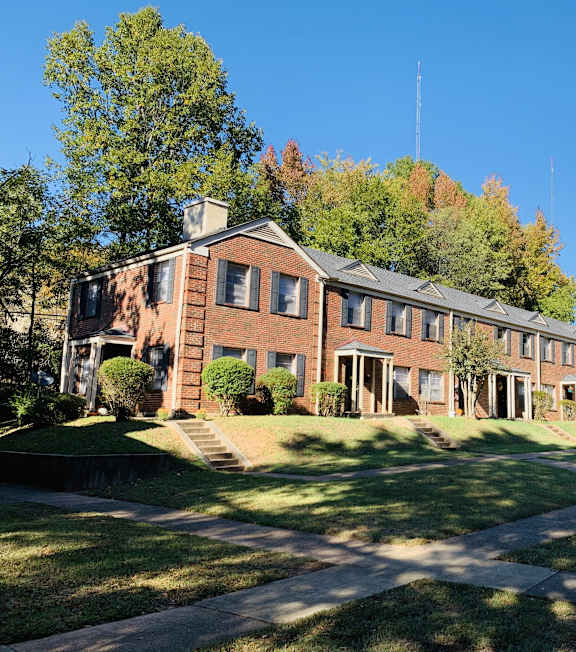 a large brick building with a lawn and trees