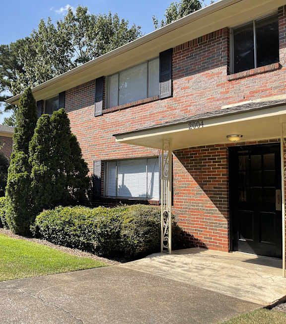 a brick house with a sidewalk in front of it