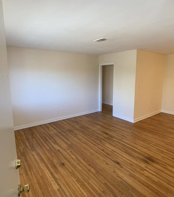an empty living room with wood flooring and white walls