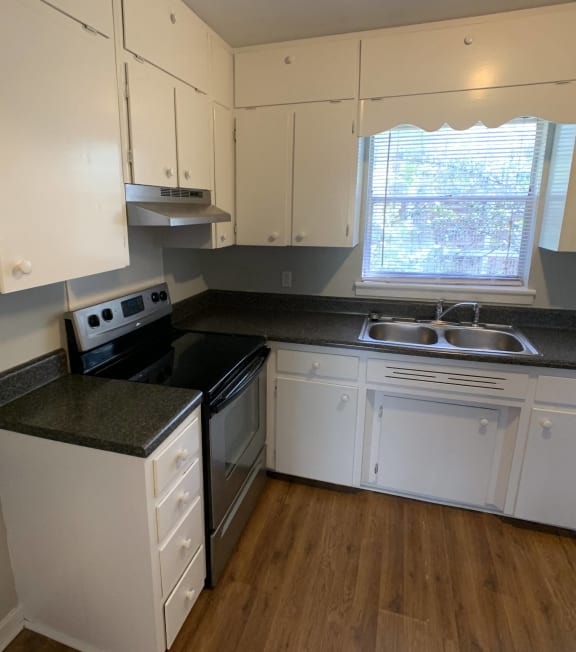 an empty kitchen with white cabinets and black counter tops