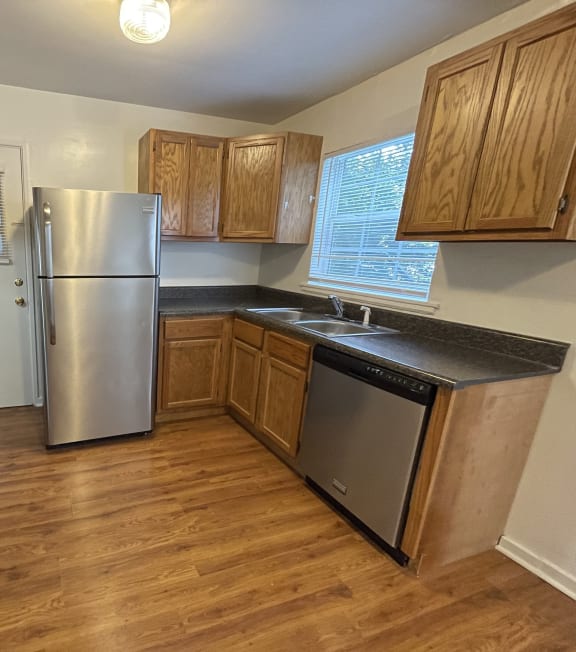 an empty kitchen with wooden floors and stainless steel appliances
