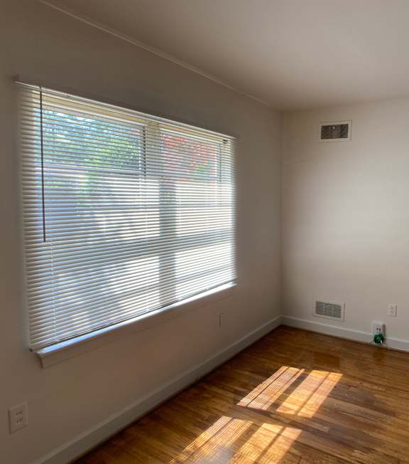 an empty living room with a large window and wooden floors