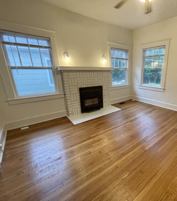 an empty living room with wood floors and a fireplace