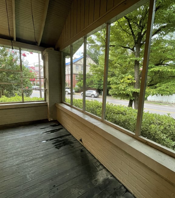 a large porch with large windows overlooking a street and trees