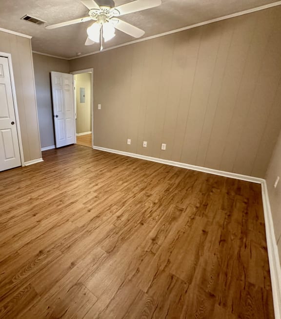 an empty living room with wood floors and a ceiling fan
